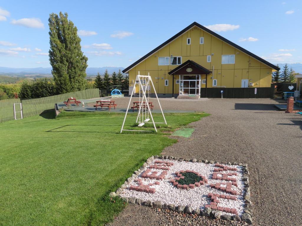 a large yellow barn with a flower arrangement in the yard at B&B Ken&Mary in Biei
