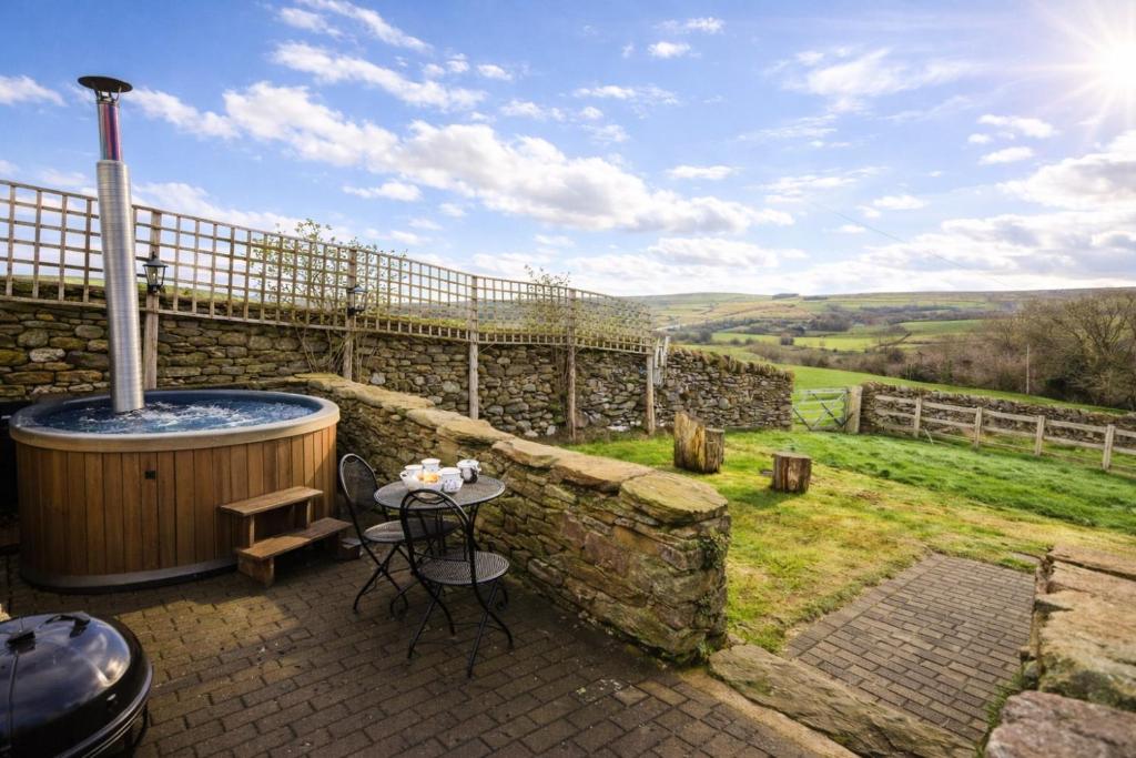 a hot tub on a patio with a stone wall at Finest Retreats - Weardale Shepherds Hut in Bishop Auckland