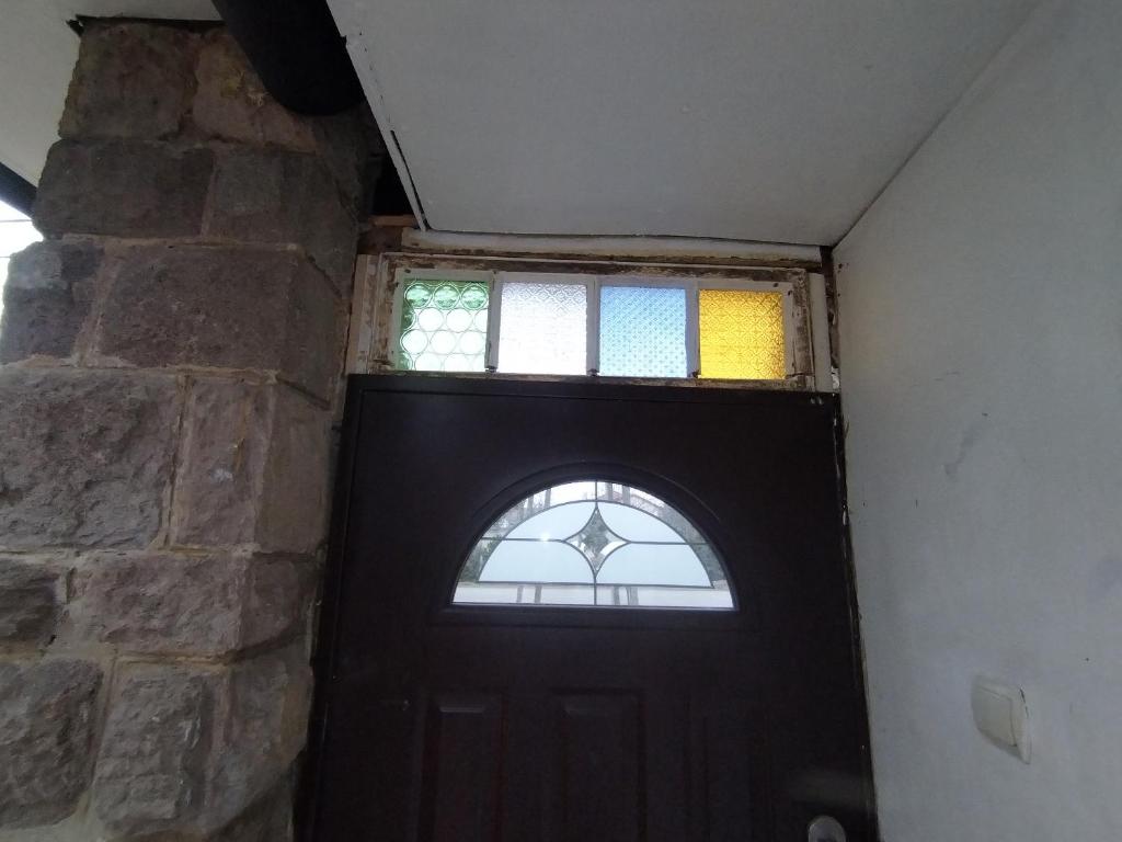 a black door with a window in a stone wall at InterSoul Apartman in Gyöngyös