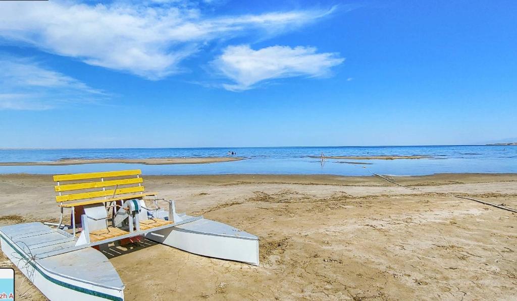 a boat on a beach with a yellow bench at Aydarkul Beach in Taldy