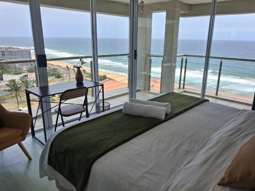 a bedroom with a bed with a table and a view of the ocean at 511 Umdloti Resort 1 bed beachfront Apartment self catering Great Sea View in Umdloti