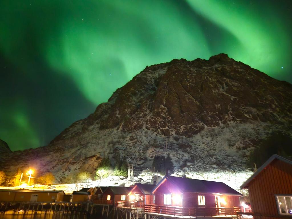 an image of the aurora borealis over a mountain at Sjøhaug Rorbu, Fishcermanns cabin in Moskenes