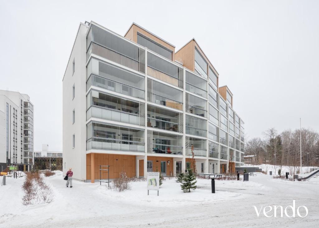 a building in the snow with a person in front of it at LuxHOMES Studio in Tapiola in Espoo