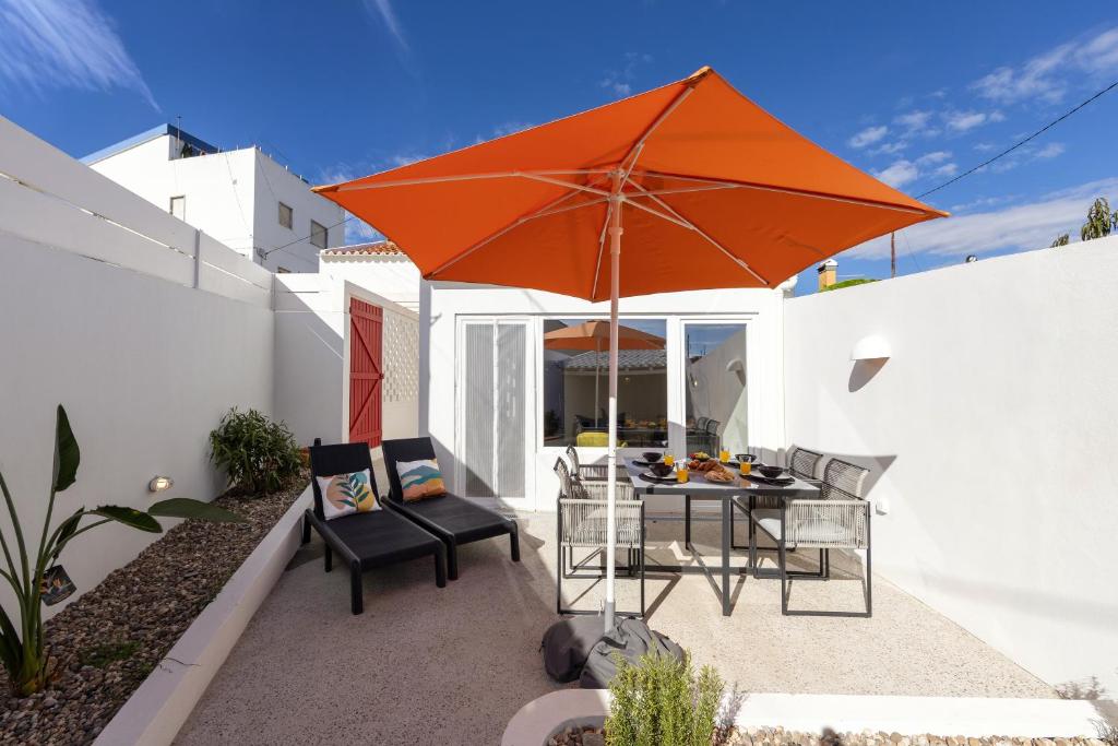 a patio with an orange umbrella and a table and chairs at The Bliss House in Lourinhã