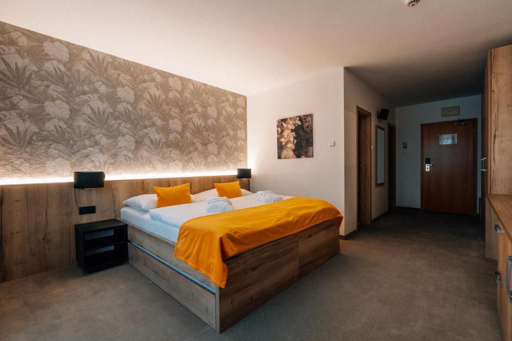 a bedroom with a large bed with orange sheets at Rodinný Hotel Hubert High Tatras in Vysoké Tatry