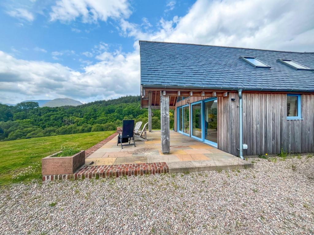 a house with a deck and a chair on a hill at Achandoilach House in Strathcarron
