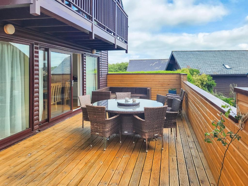 a patio with a table and chairs on a deck at Cedar Lodge - Retallack in Saint Columb Major