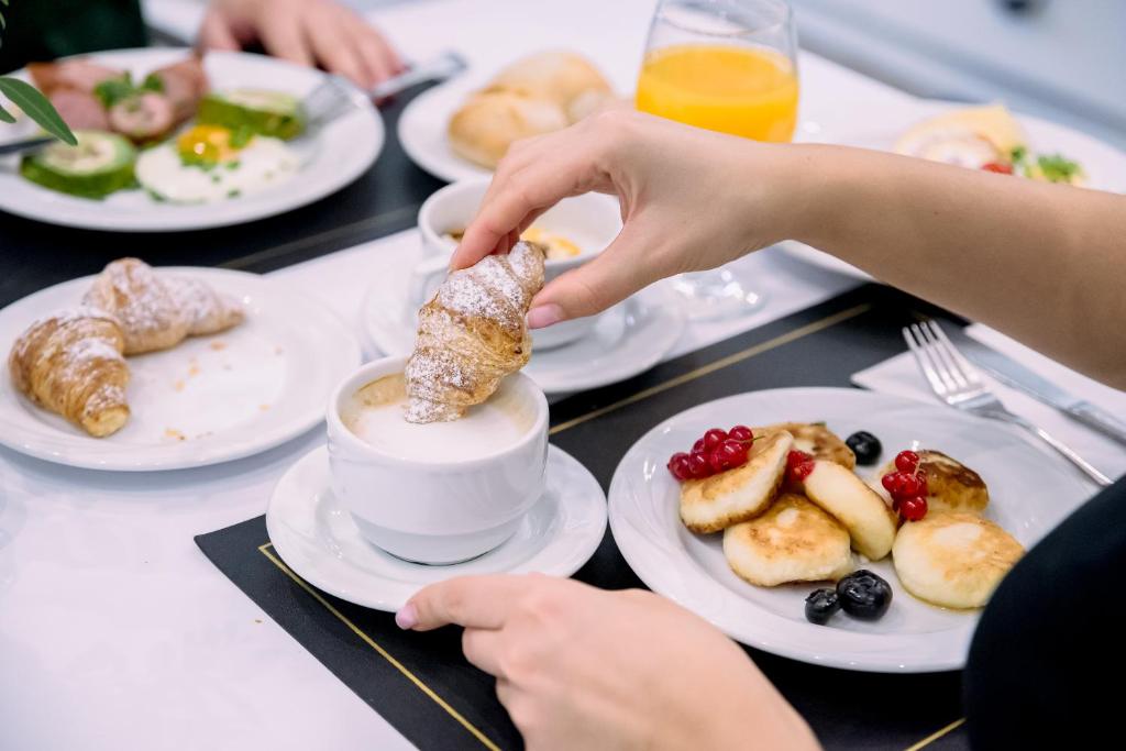 a person eating food on a table with plates of food at Hotel Lamberton in Ołtarzew