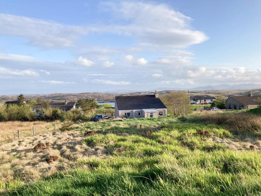 a house in the middle of a field of grass at Dalvista Cottage in Leurbost
