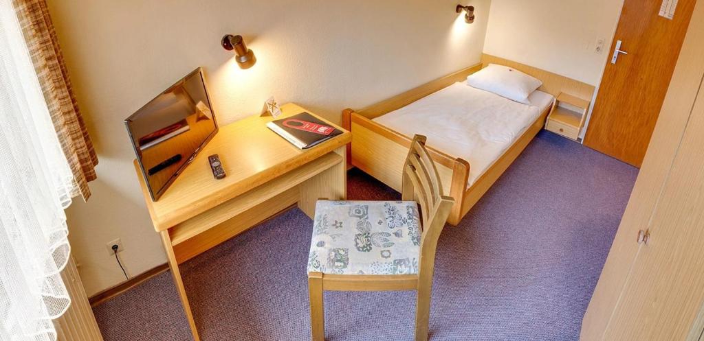 a small room with a desk and a bed and a chair at Pension Keinath in Stuttgart