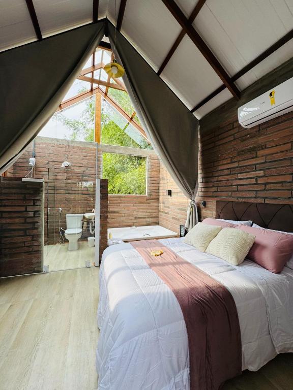 a bedroom with a large bed and a bathroom at Pousada Jardins da Gastehaus in Triunfo