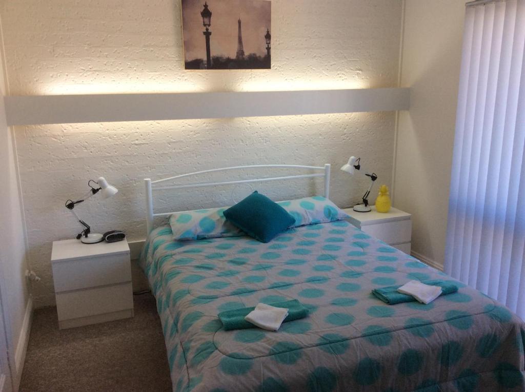 ein Schlafzimmer mit einem Bett mit zwei Nachttischen und zwei Lampen in der Unterkunft Como Lodge in Merimbula