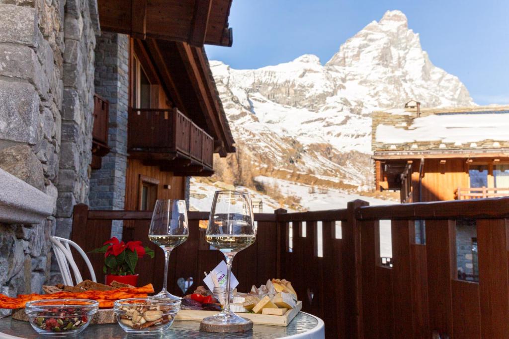 a table with wine glasses on a balcony with a mountain at Maison Carrel Elegant 4 in Breuil-Cervinia