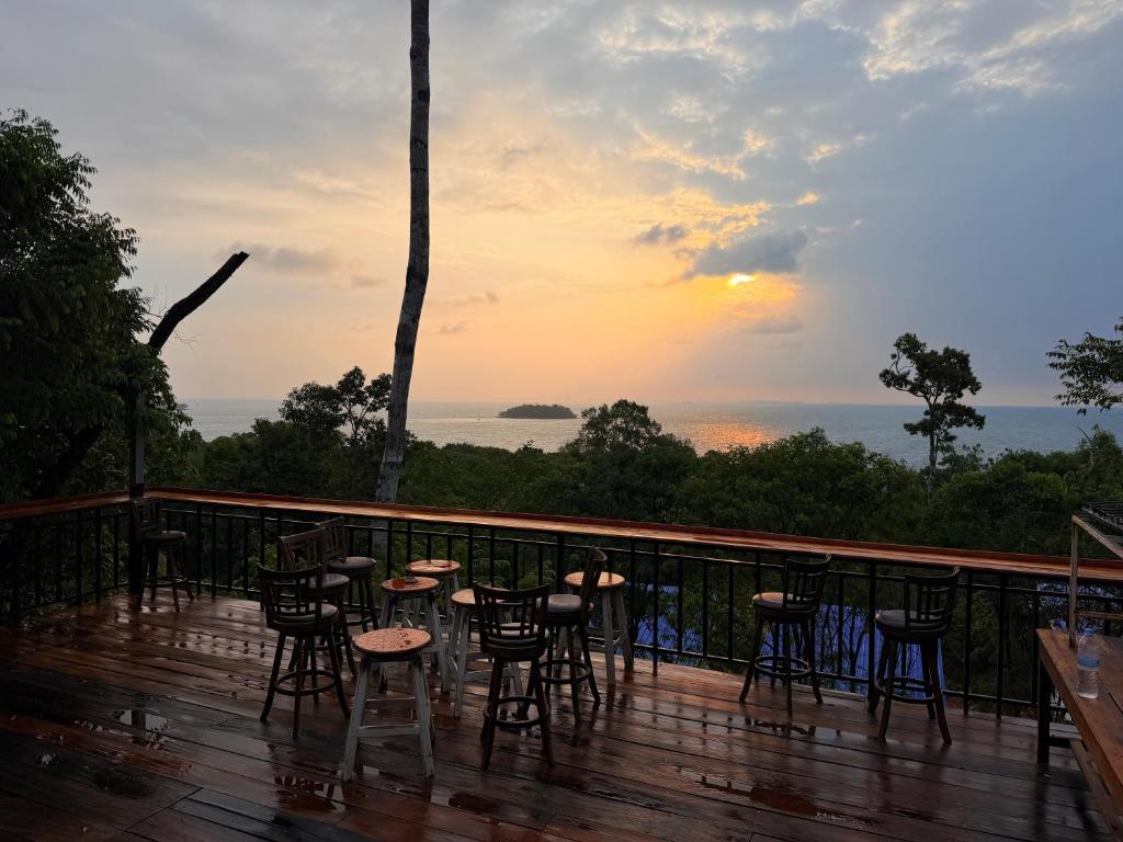 a deck with chairs and tables at sunset at Hillside Hostel & Bungalows in Kaôh Rŭng (3)