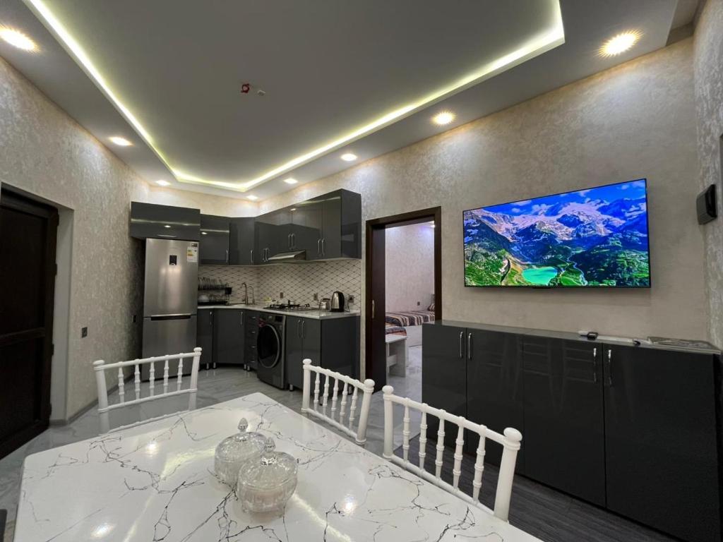 a kitchen with a white table and a tv on the wall at Ganja VIP Home in Ganja