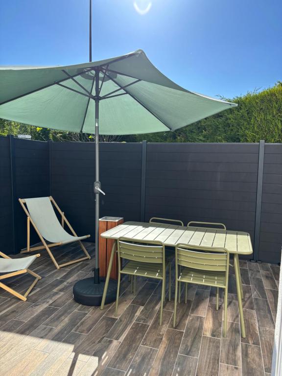 a table and chairs and an umbrella on a patio at Cottage Larris - proche Aéroport - navette Gare in Beauvais