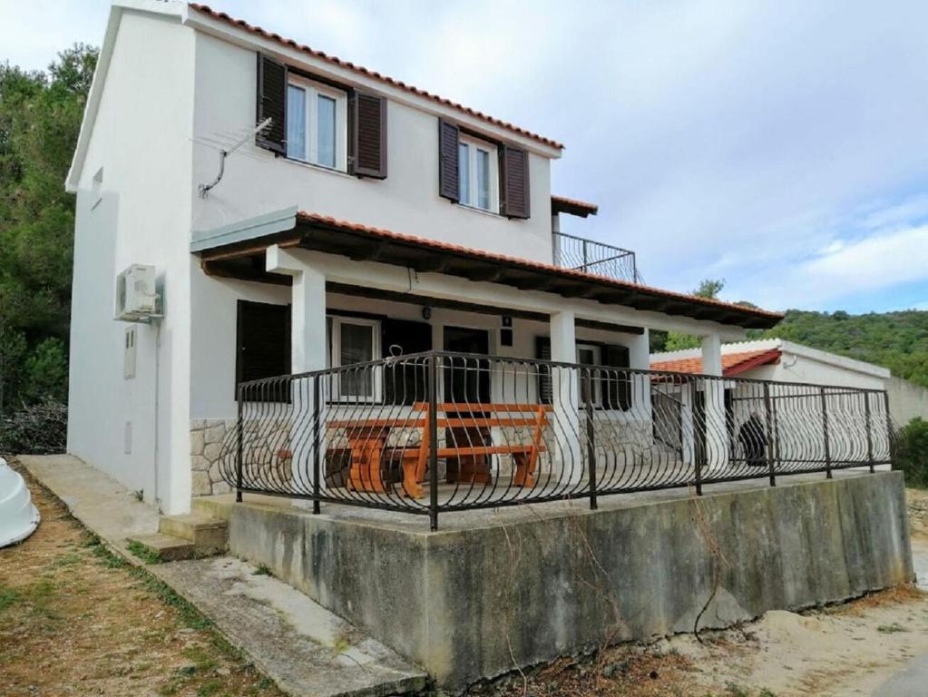 a white house with a fence on a balcony at Apartments Branko in Podstražje