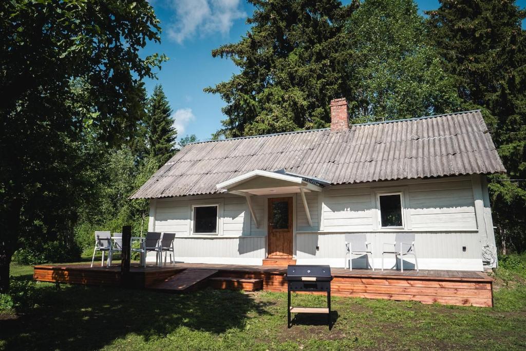 a white house with chairs on a deck at Peaceful Forest Cabin in Nature in Paluküla