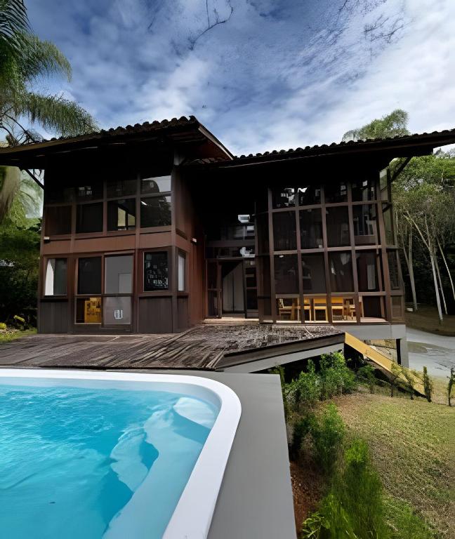 a house with a swimming pool in front of it at Beautiful View Villa: Sea and Forest in São Francisco do Sul