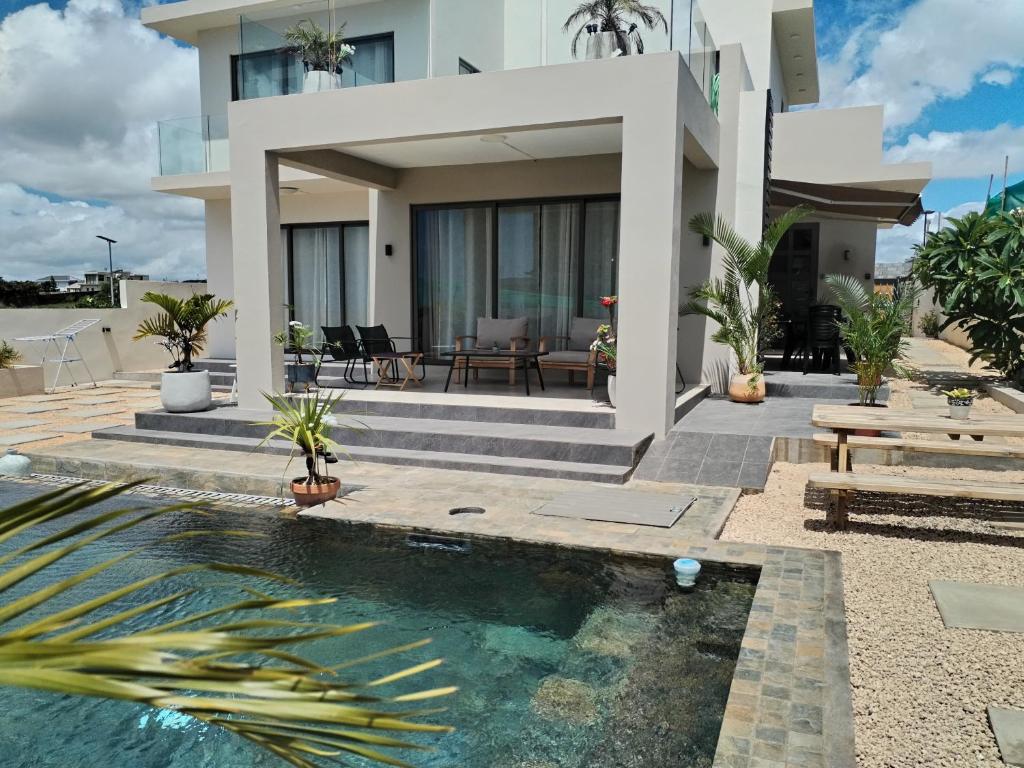 a house with a swimming pool in front of a house at Fleur&Sel Westcoast Villa in Flic-en-Flac