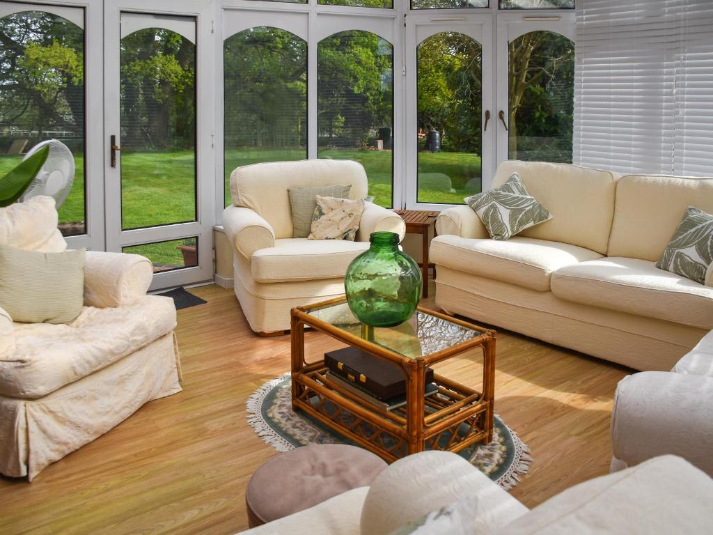 a living room with white furniture and a vase on a table at Swallowdale in Flordon
