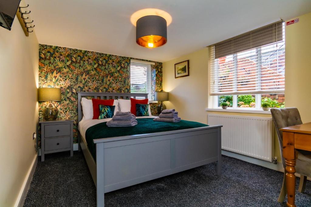a bedroom with a bed and a desk and windows at The Music Rooms in Bewdley