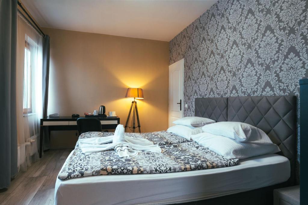 a bedroom with a bed with a headboard and a desk at Végvári Hotel Eger in Eger