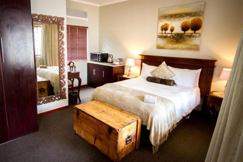 a bedroom with a large bed with a wooden trunk at the end at The Black Swann in Queenstown