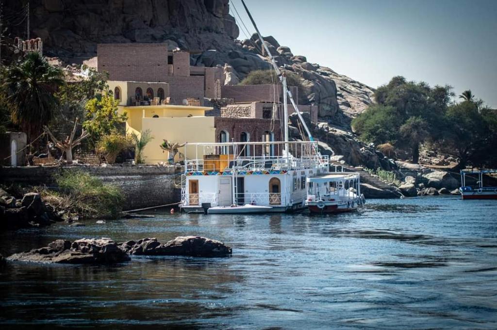 a boat is docked on a river next to a building at Nile Dream Yacht in Jazīrat Salūjah