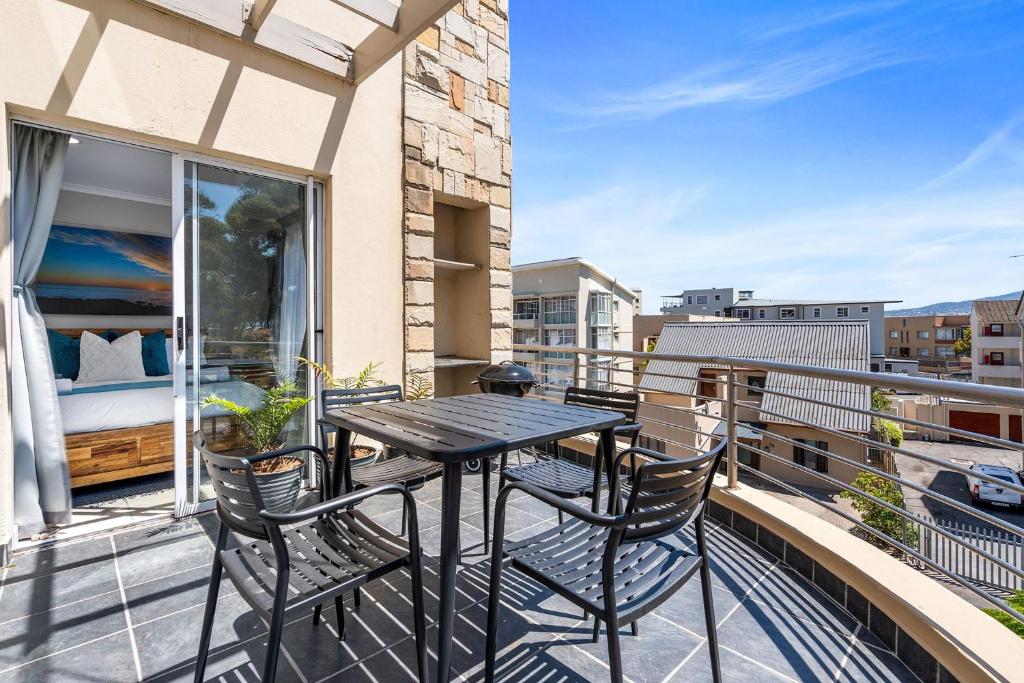 a balcony with a table and chairs and a bed at Coral Grove in Strand