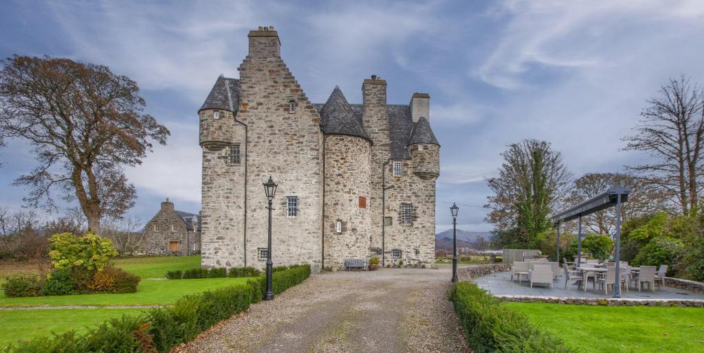 an old stone castle with tables and chairs in front of it at Barcaldine Castle in Oban