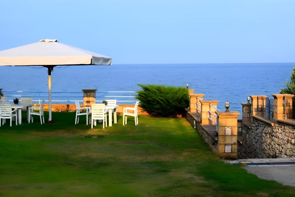 a table and chairs with an umbrella and the ocean at Alexandros Beachfront Apartments near Petalidi with Private Sunbeds & Sea View in Kalamaki Messinia