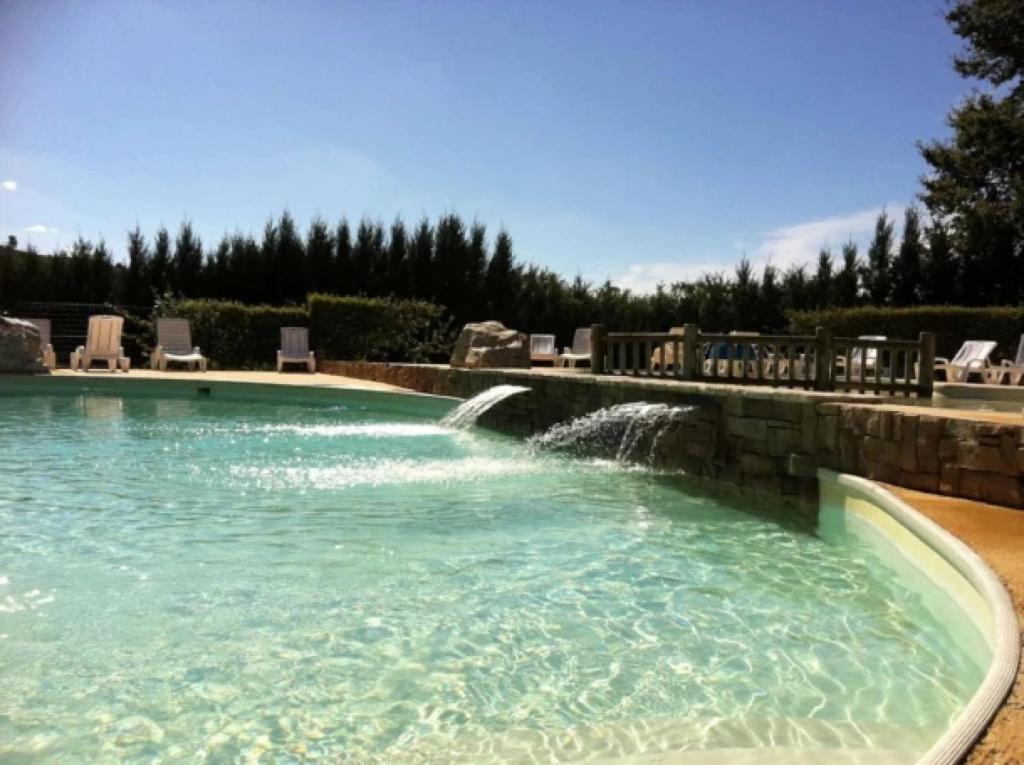 a swimming pool with a waterfall in a yard at ZEcamping 4 étoiles animaux acceptés tennis pataugeoire in Tamniès