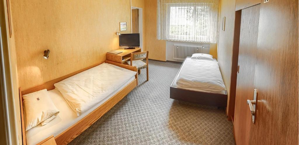 a small room with two beds and a television at Hotel Keinath Stuttgart in Stuttgart