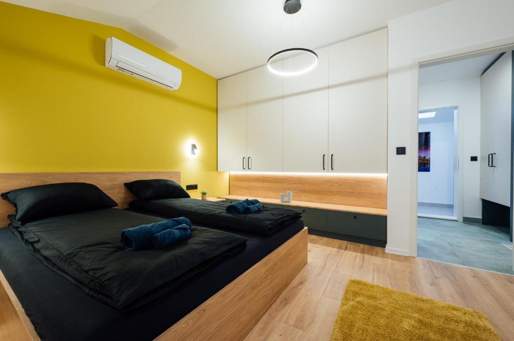 a bedroom with a bed and a yellow wall at KNB City Suites in Odorheiu Secuiesc