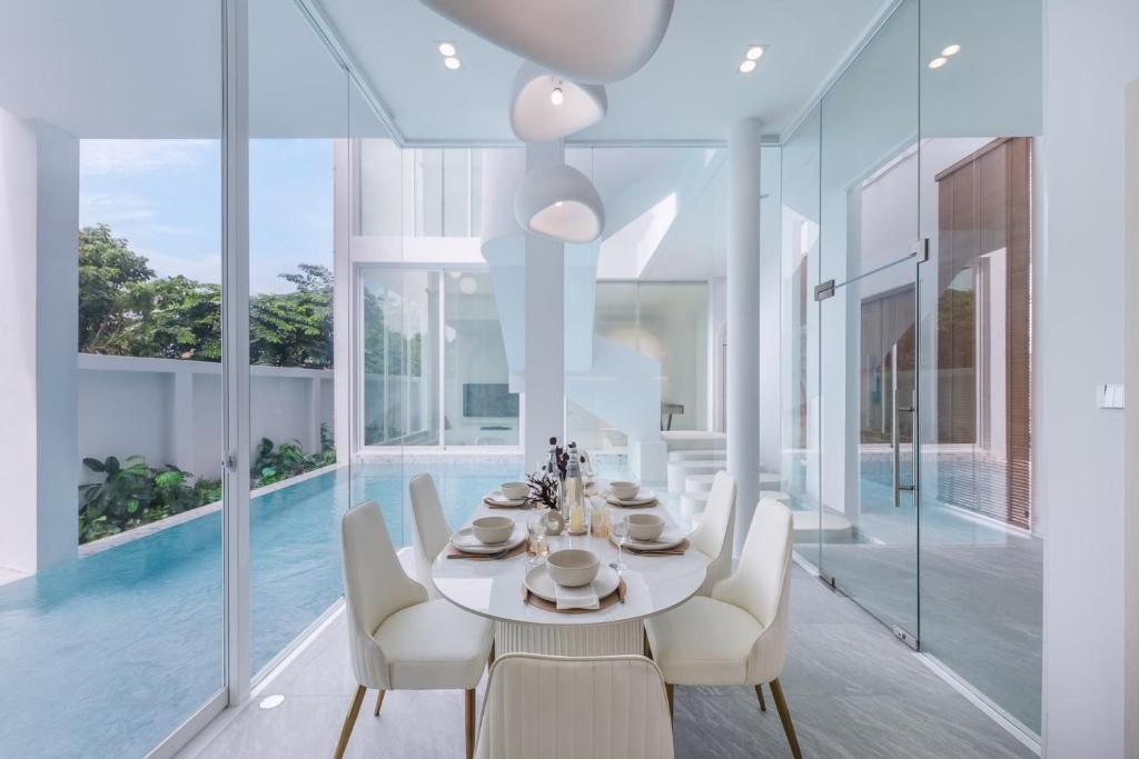 a dining room with a table and chairs and a pool at The Pool Space - ICONIC Pool Villa in Ban Huai Yai