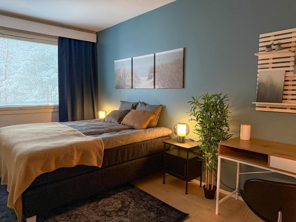 a bedroom with a bed with blue walls and a desk at Tilava ja elegantti kolmio in Kokkola