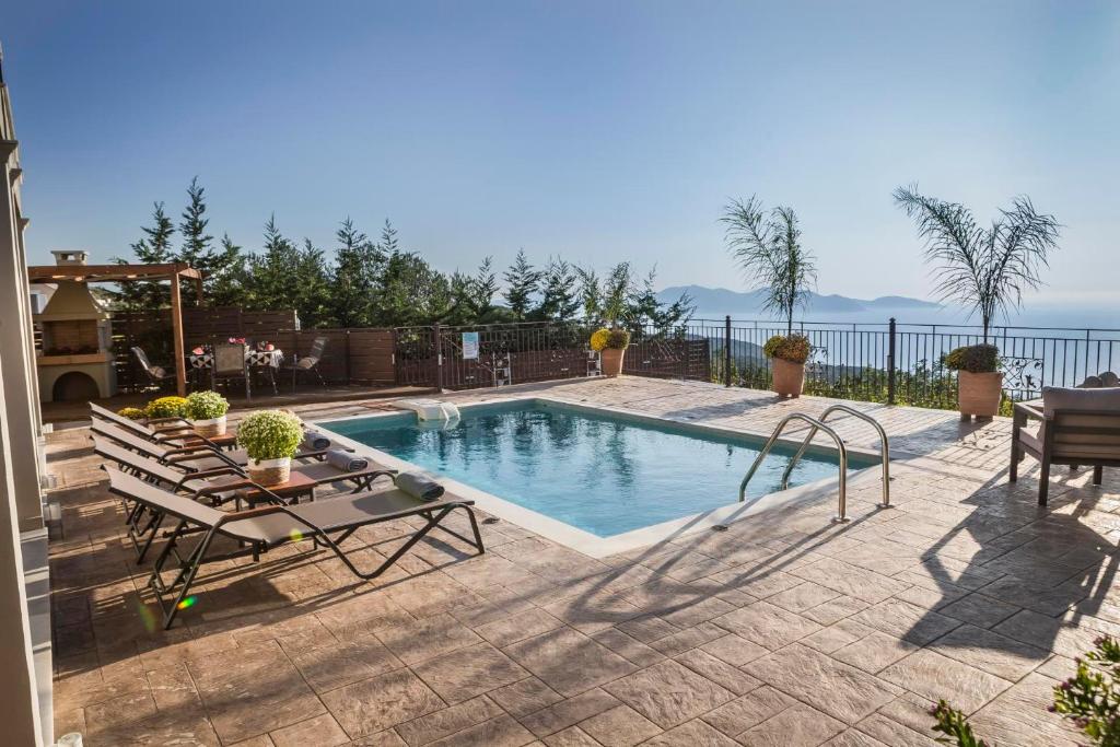a swimming pool with two chairs and a table at Vasilikades by Vintage Travel in Fiskardo