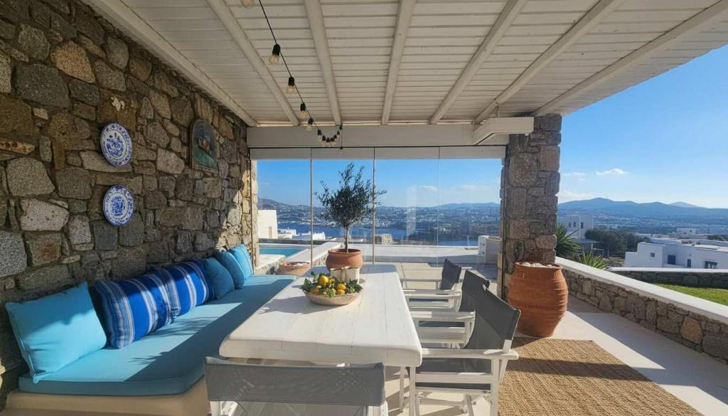 a patio with a table and chairs and a stone wall at Stunning Sea-View Villa w Access to Shared Pools in Mikonos