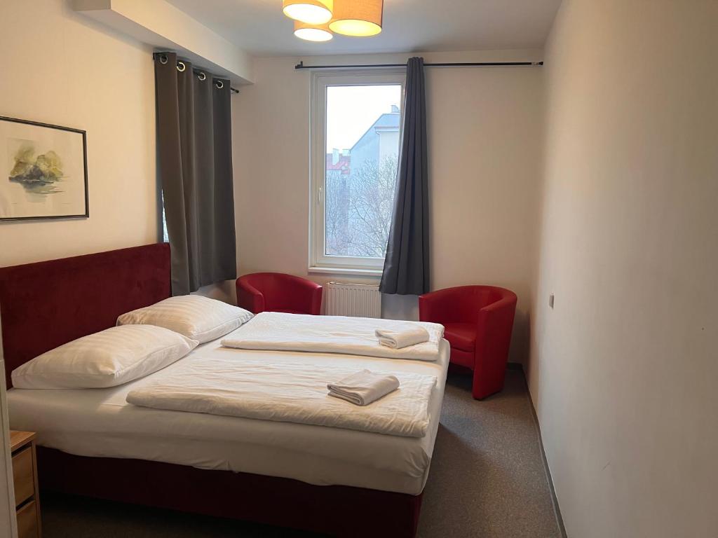 a bedroom with two beds and two red chairs at Hotel Astral Vienna in Vienna