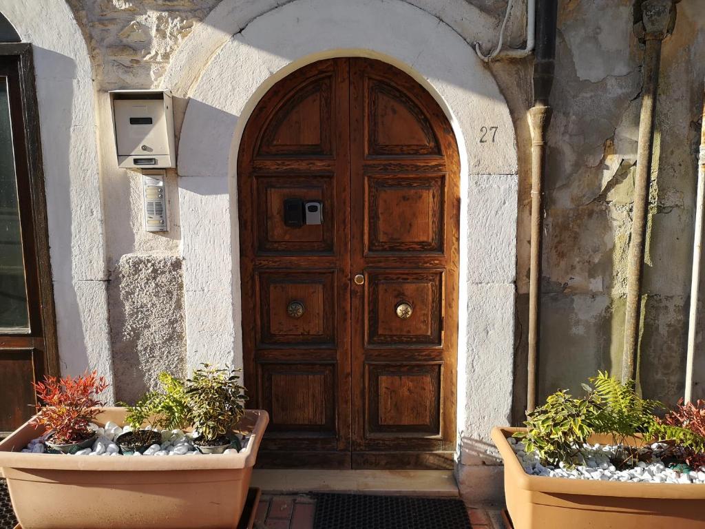 a wooden door in a building with two potted plants at Alla Cattedrale - Locazione Turistica in Sulmona