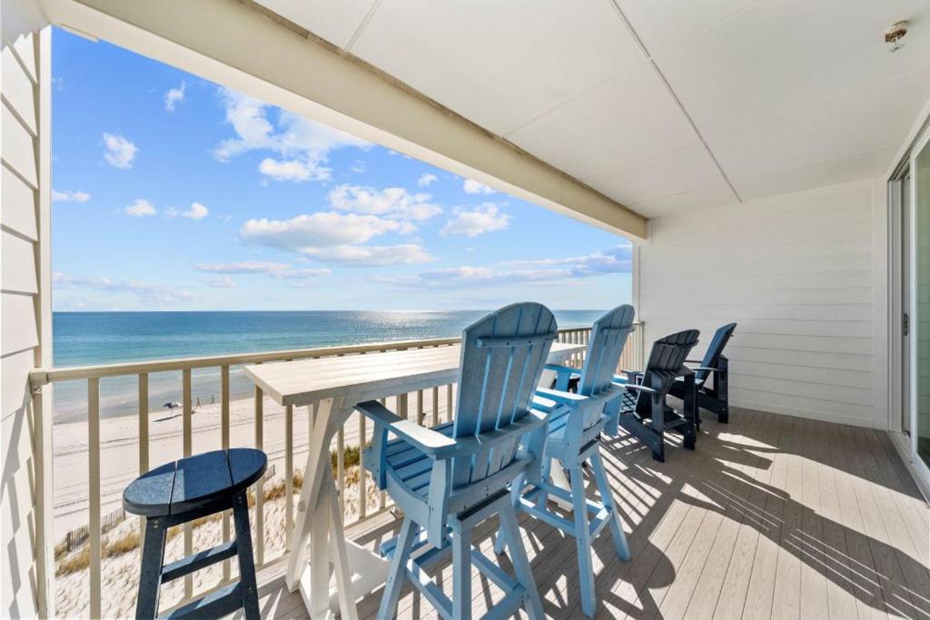 a balcony with blue chairs and a table and the ocean at Sea Glass 404 by Youngs Suncoast in Gulf Shores