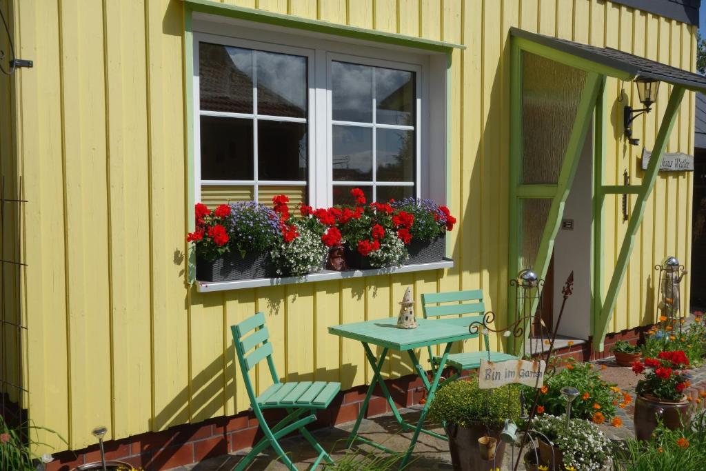a yellow house with a table and chairs and flowers in a window at Ferienwohnung Anna in Benneckenstein