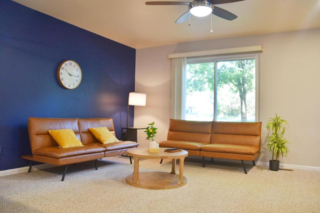 a living room with two leather couches and a clock at Exclusive 2B1B Prime Location in Sylvan Lake