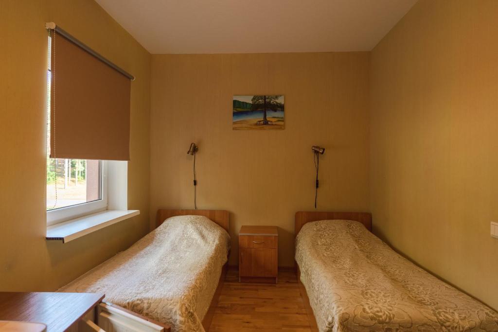 two beds in a room with a window at Alutaguse Tervisespordikeskuse Peamaja in Vasavere