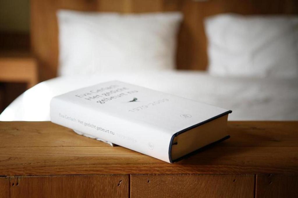 a book sitting on top of a table next to a bed at Poëziehotel Surplace in Bever