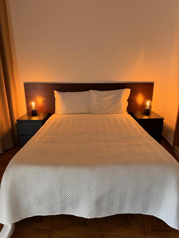 a bedroom with a bed with two lamps on two tables at Romeu in Quarteira