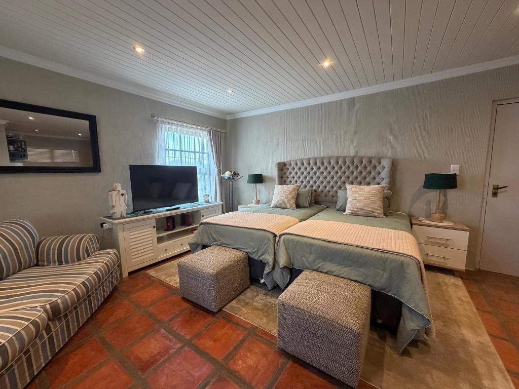 a bedroom with two beds and a flat screen tv at Windkraal Farm Studio in Bonnievale