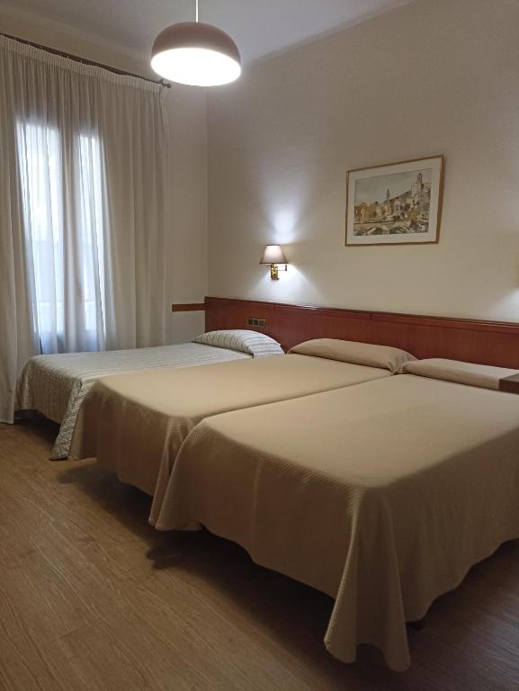 two beds in a hotel room with a window at Hotel Europa in Girona