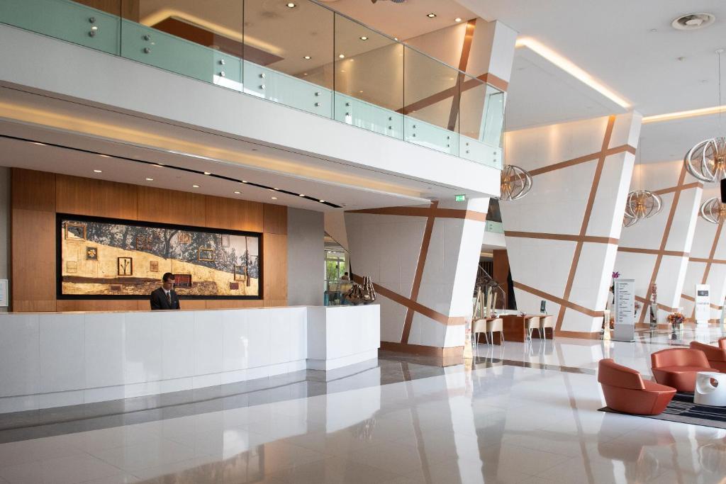 A spacious, contemporary lobby with a white reception desk and lounge seating.